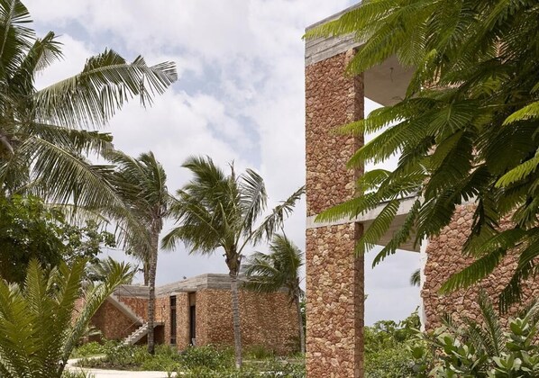 Een resort met stenen zuilen, palmbomen en een gebouw met een stenen gevel.