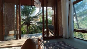 Una habitación con una cama, vistas a palmeras y un ventanal grande.