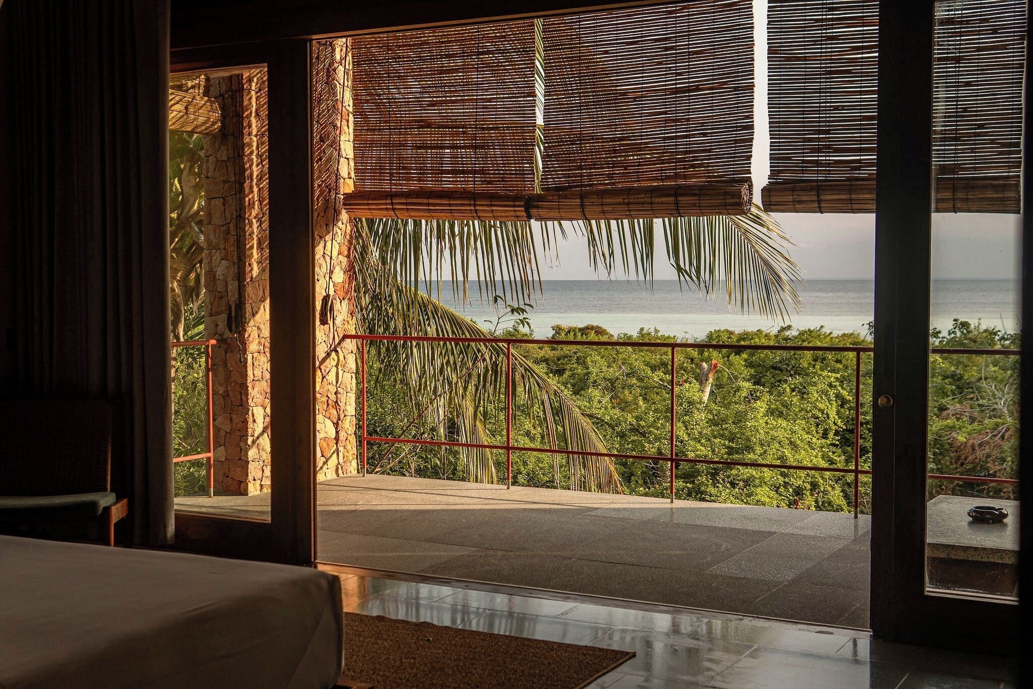 Quarto com vista para o oceano, varanda com guarda-corpo e porta para o exterior.