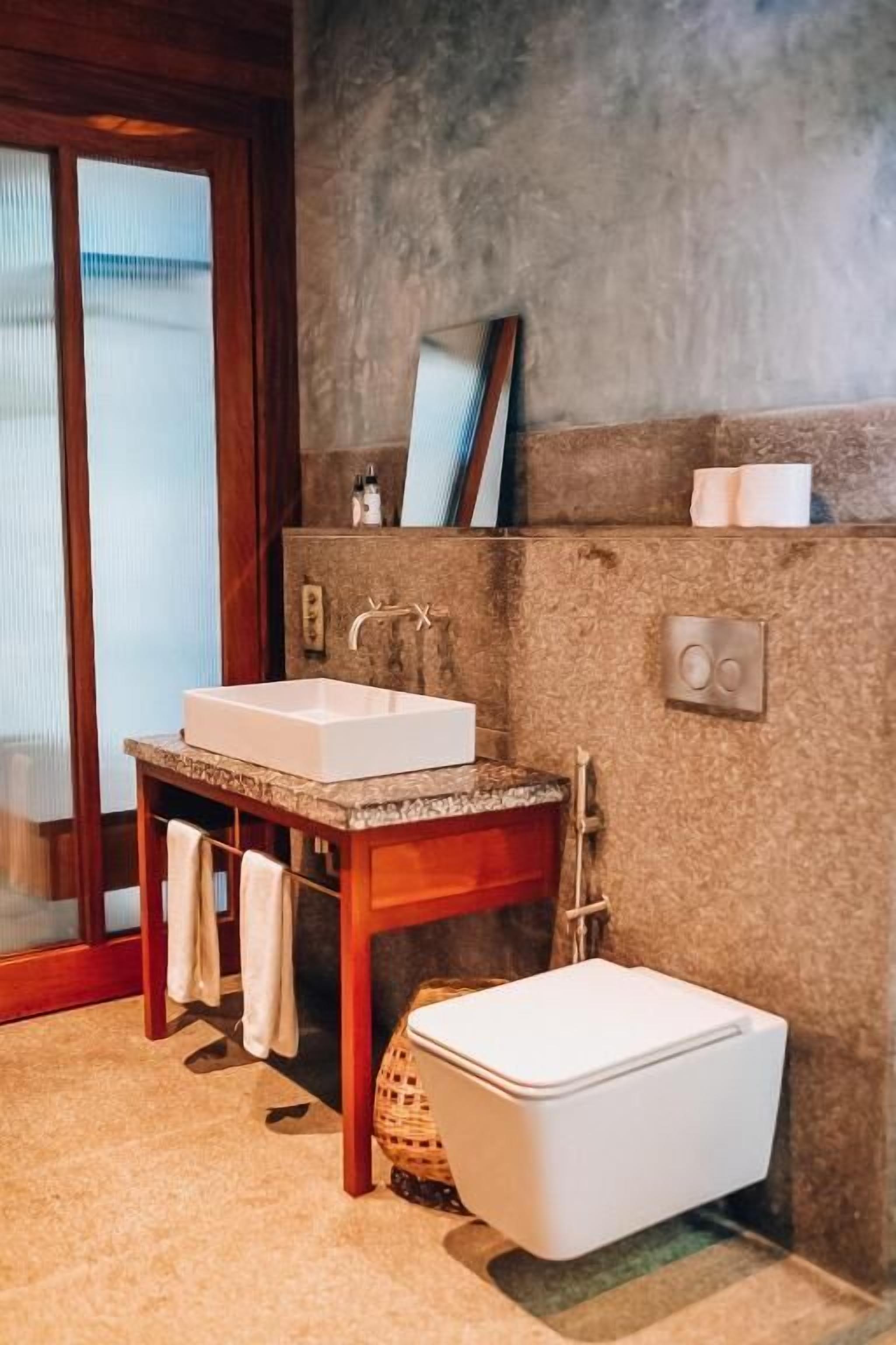 Ein Badezimmer mit einem Holzinlay, einem weißen Waschbecken, einer Toilette und einem Handtuchhalter.