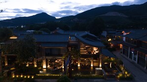 Un edificio de estilo japonés tradicional con un interior moderno, rodeado de un jardín paisajístico y vistas a montañas.