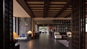Un vestíbulo amplio con techo alto, vigas de madera oscura, pared de piedra y una pared decorada con objetos enmarcados.