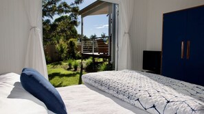 Ein Schlafzimmer mit Bett, Fernseher und Blick auf einen Garten.