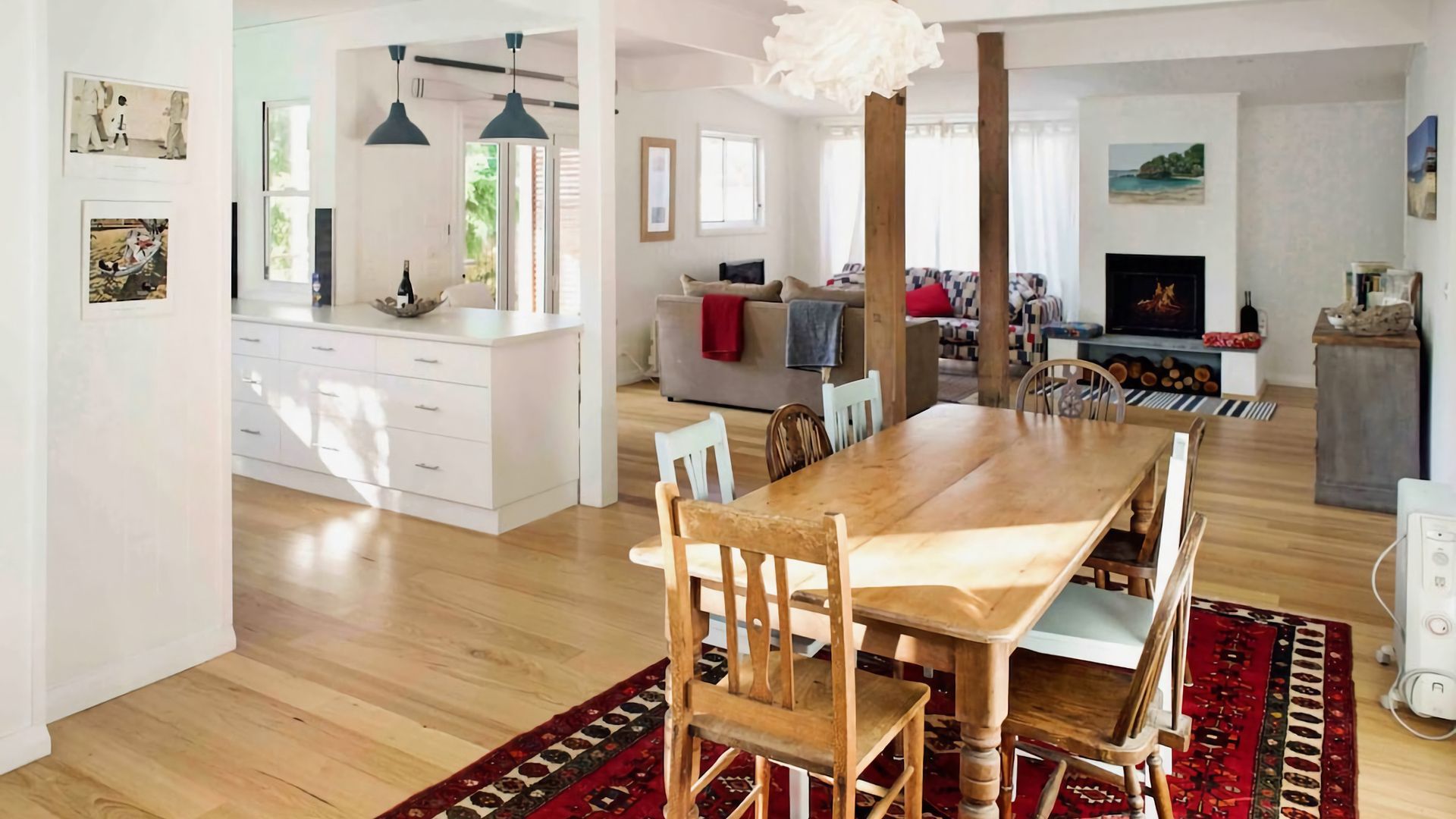 A spacious living area with a wooden dining table, chairs, a sofa, and a fireplace.