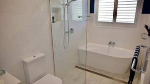 A modern bathroom with a glass-enclosed shower, a standalone toilet, and a freestanding bathtub. - Alora Cottage in the heart of Bendalong (Bendalong)