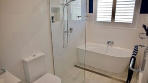 Une salle de bain moderne dotée d’une douche à parois de verre, de toilettes séparées et d’une baignoire sur pieds.