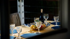 A table set with wine glasses, a bottle, and a fruit bowl. - Alora Cottage in the heart of Bendalong (Bendalong)