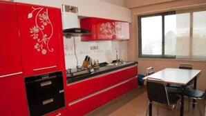 Una cocina con armarios rojos, una encimera blanca y una zona de comedor con mesa y sillas.