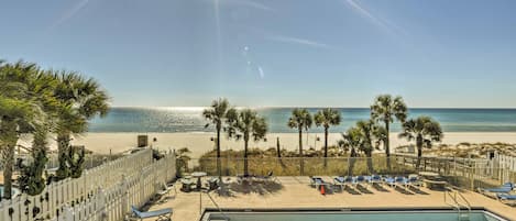 Ein Poolbereich mit Liegestühlen, einem Pool und Blick auf Strand und Meer.