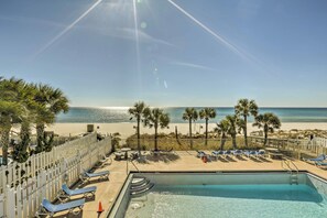 A pool area with lounge chairs, a pool, and a view of the beach and ocean. - Arcade & Pool Access: Panama City Beach Townhome! (Panama City Beach)