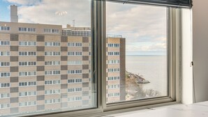 A view through a large window of a building with a checkered facade and a body of water in the background. - 6 Mi to Downtown Cleveland: Lakeview Condo! (Lakewood)