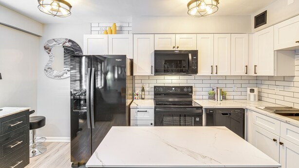 A modern kitchen with white cabinets, stainless steel appliances, and a marble countertop. - 6 Mi to Downtown Cleveland: Lakeview Condo! (Lakewood)