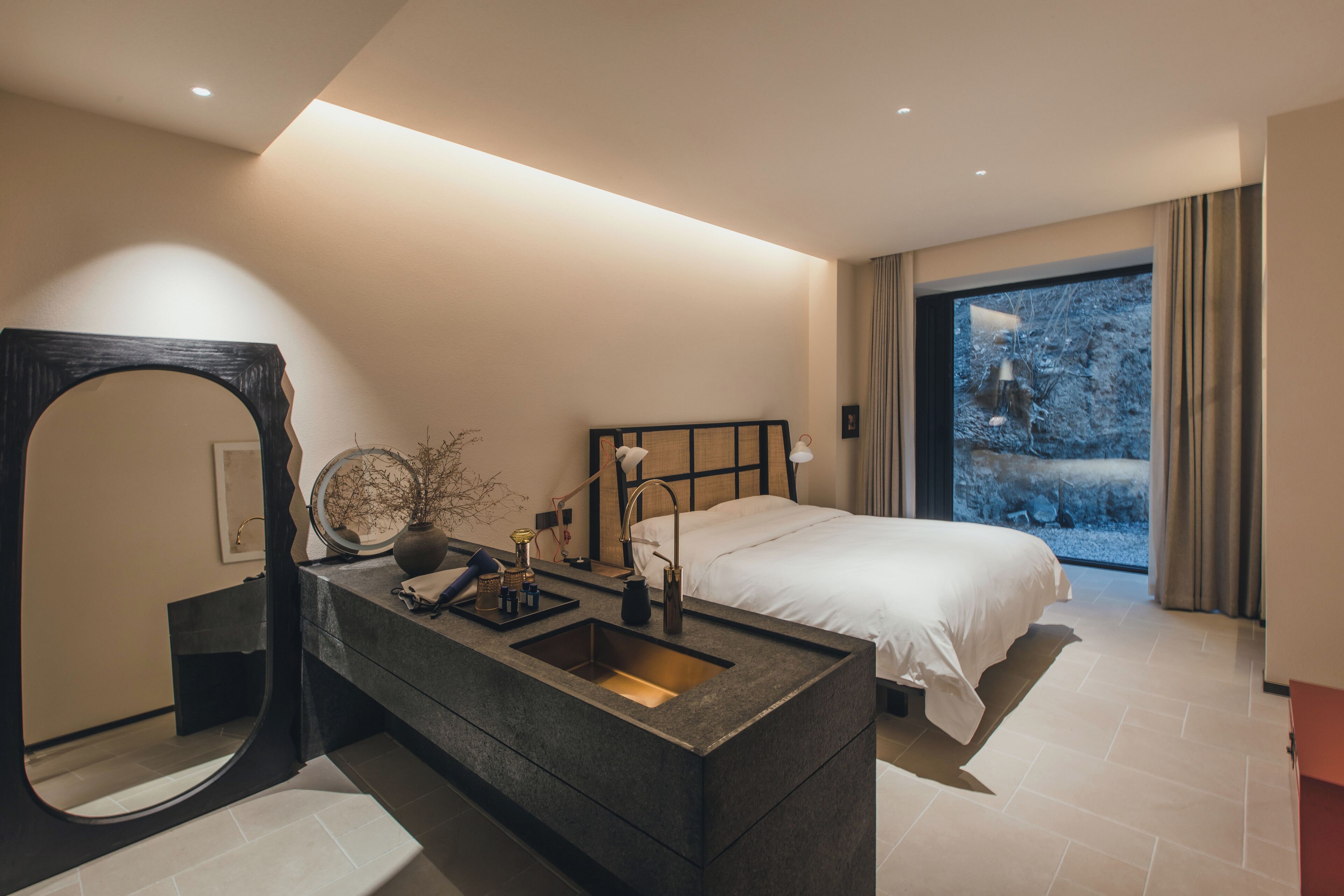 Un dormitorio moderno con una cama grande, un tocador empotrado y un espejo amplio.