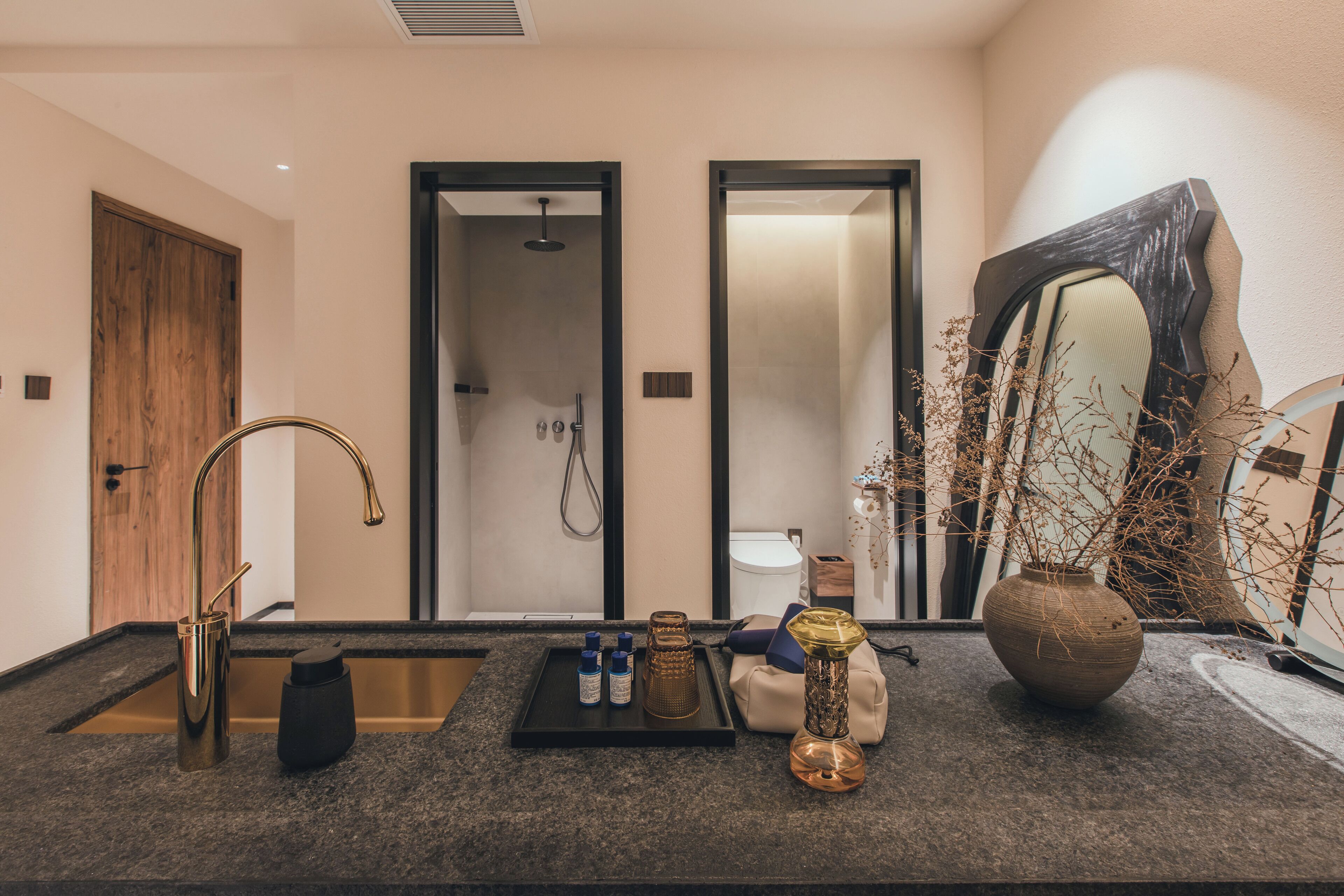 A bathroom with a sink, mirror, shower, and toilet.