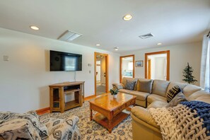 A living room with a sofa, coffee table, and TV. There are wooden doors and a small Christmas tree. - Heart of Five College Consortium! Hadley Home (Hadley)