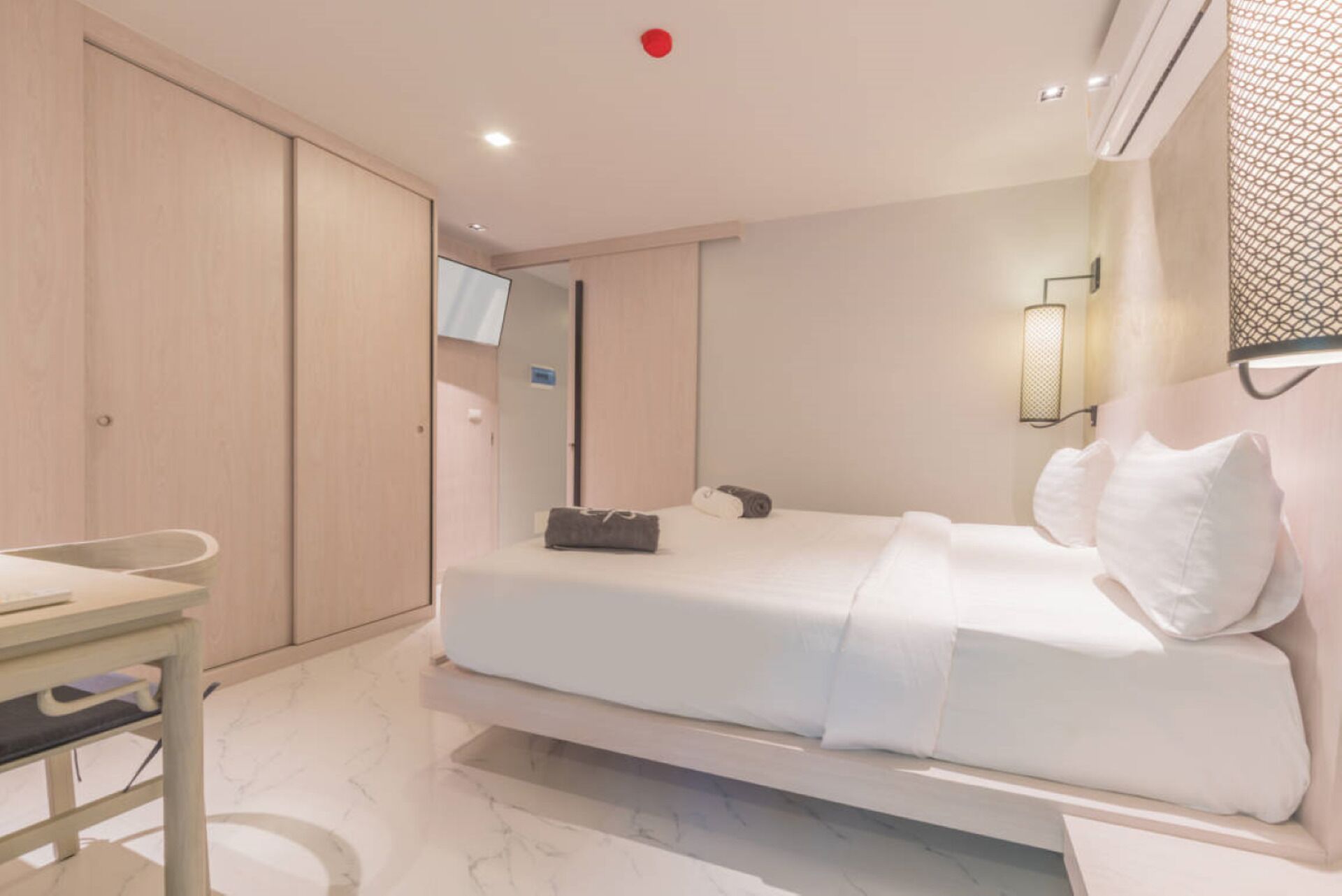 Quarto de hotel com uma cama, uma escrivaninha e um guarda-roupa.