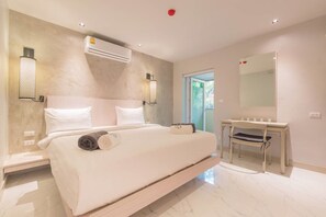 A modern bedroom with a large bed, a bedside table, a mirror, and an air conditioning unit. - Woodbridge Property at Karon Butterfly (Karon)