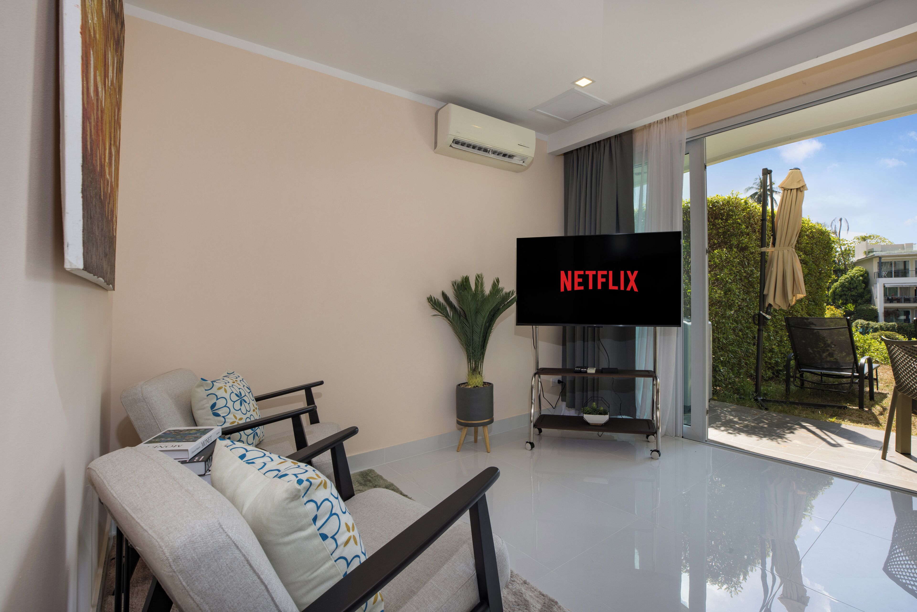 Ein modernes Wohnzimmer mit Flachbildfernseher, einer Couch, einem Couchtisch und einem Blumentopf.