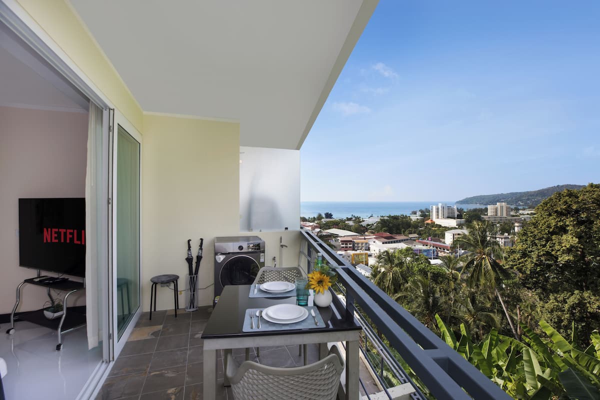 A balcony with a dining table, chairs, a TV, and a washing machine.