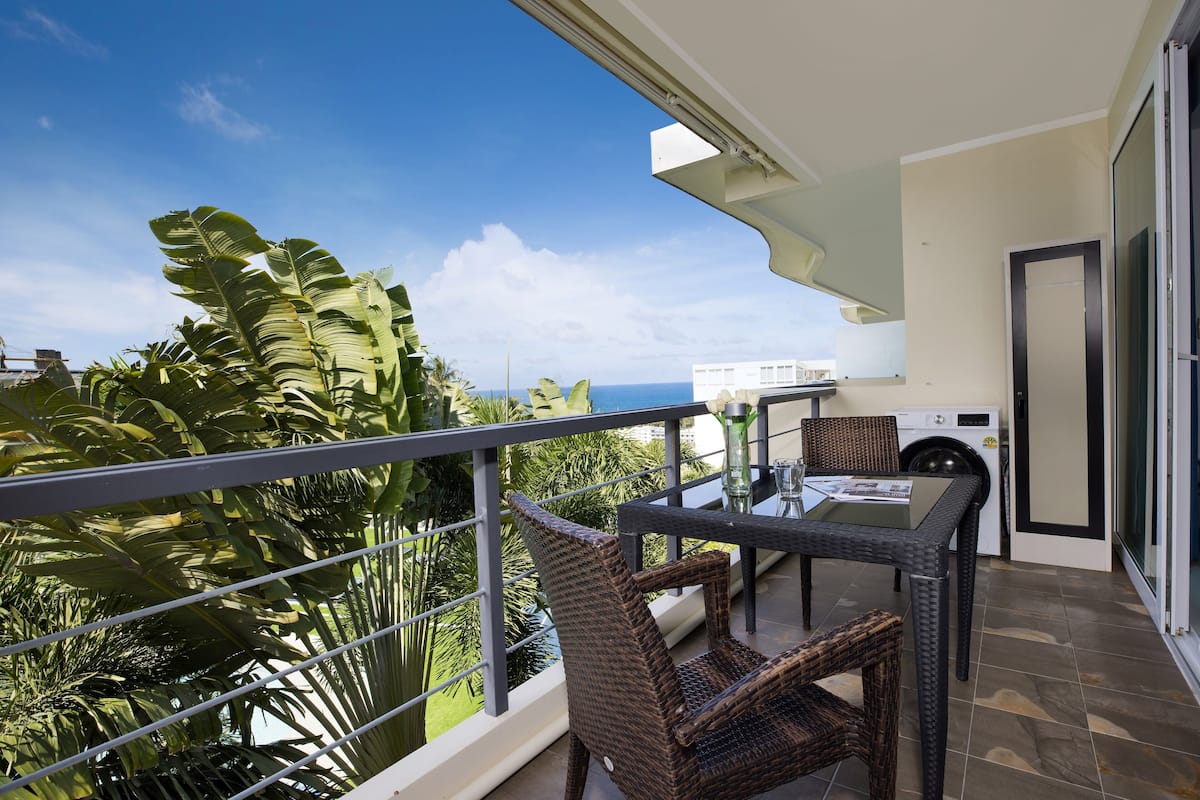 A balcony with wicker furniture, a washing machine, and a view of the ocean.
