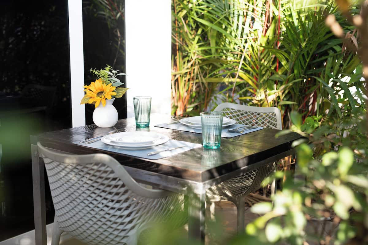 A table set for two with a white vase of sunflowers, two clear glasses, and a white plate.