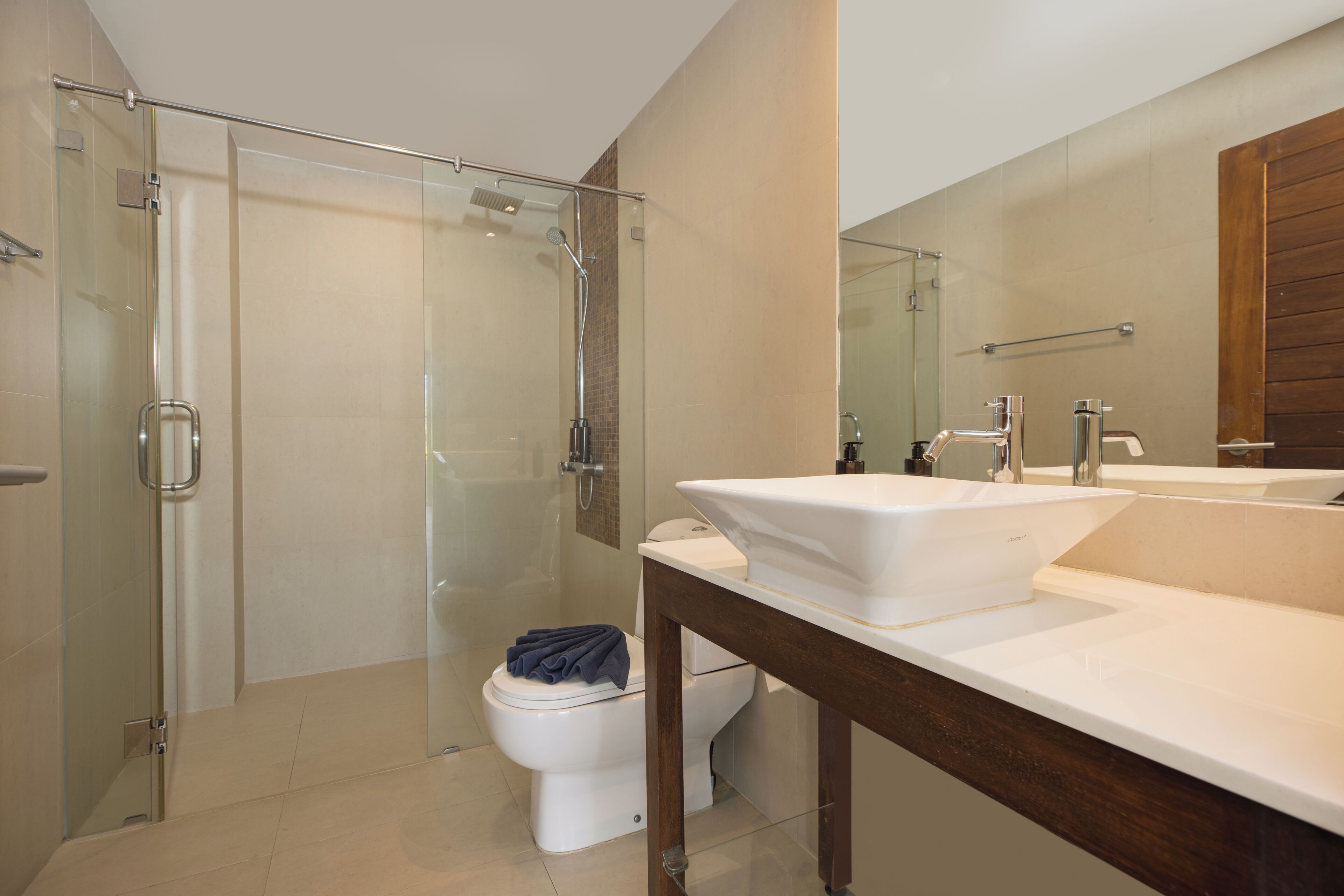 A modern bathroom with a glass-enclosed shower, a white toilet, and a double sink vanity.