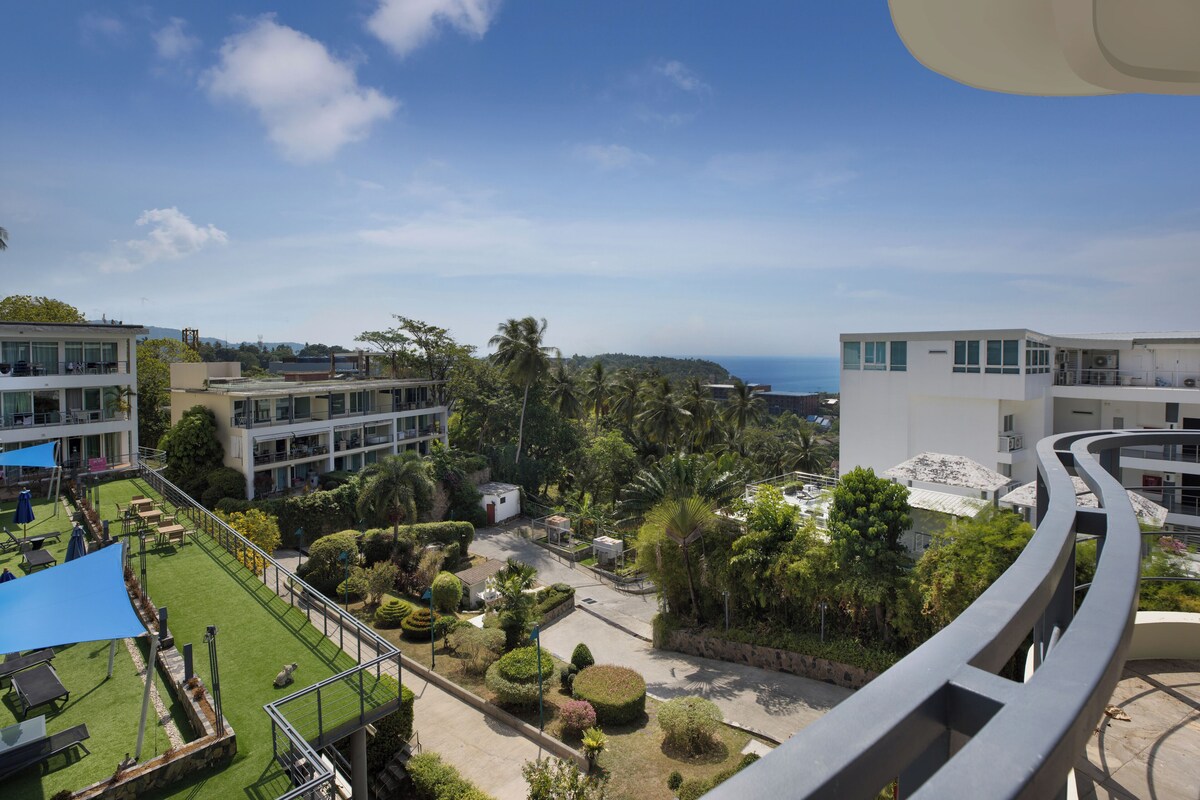 A hotel with a rooftop garden, multiple buildings, and a view of the ocean.