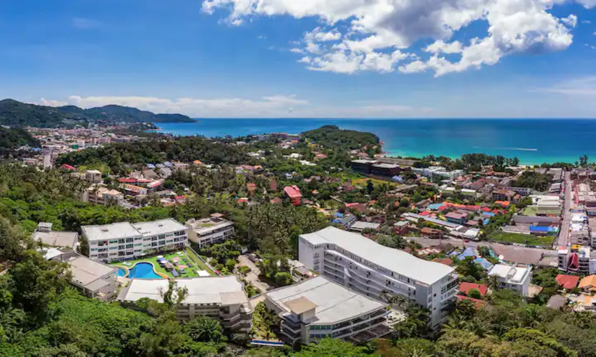 Une ville côtière qui abrite un grand hôtel doté d’une piscine, entouré d’une végétation luxuriante et offrant une vue dégagée sur la mer.