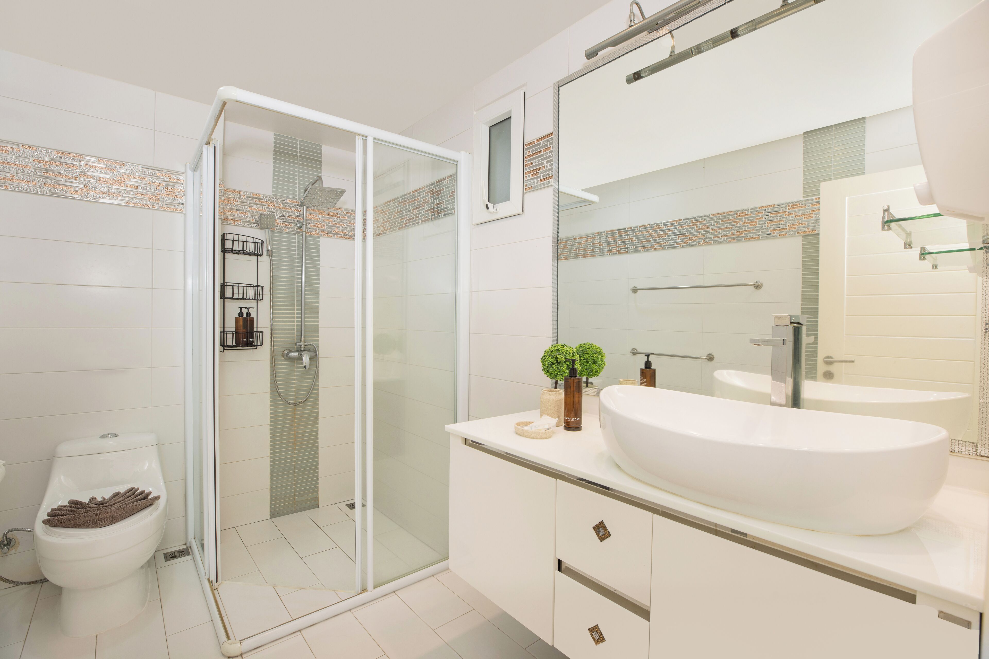 A modern bathroom with a glass shower enclosure, a white sink, and a large mirror.
