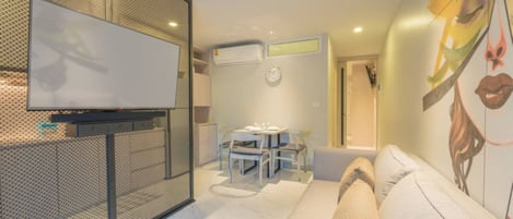 Una sala moderna con televisor, comedor y sofá.