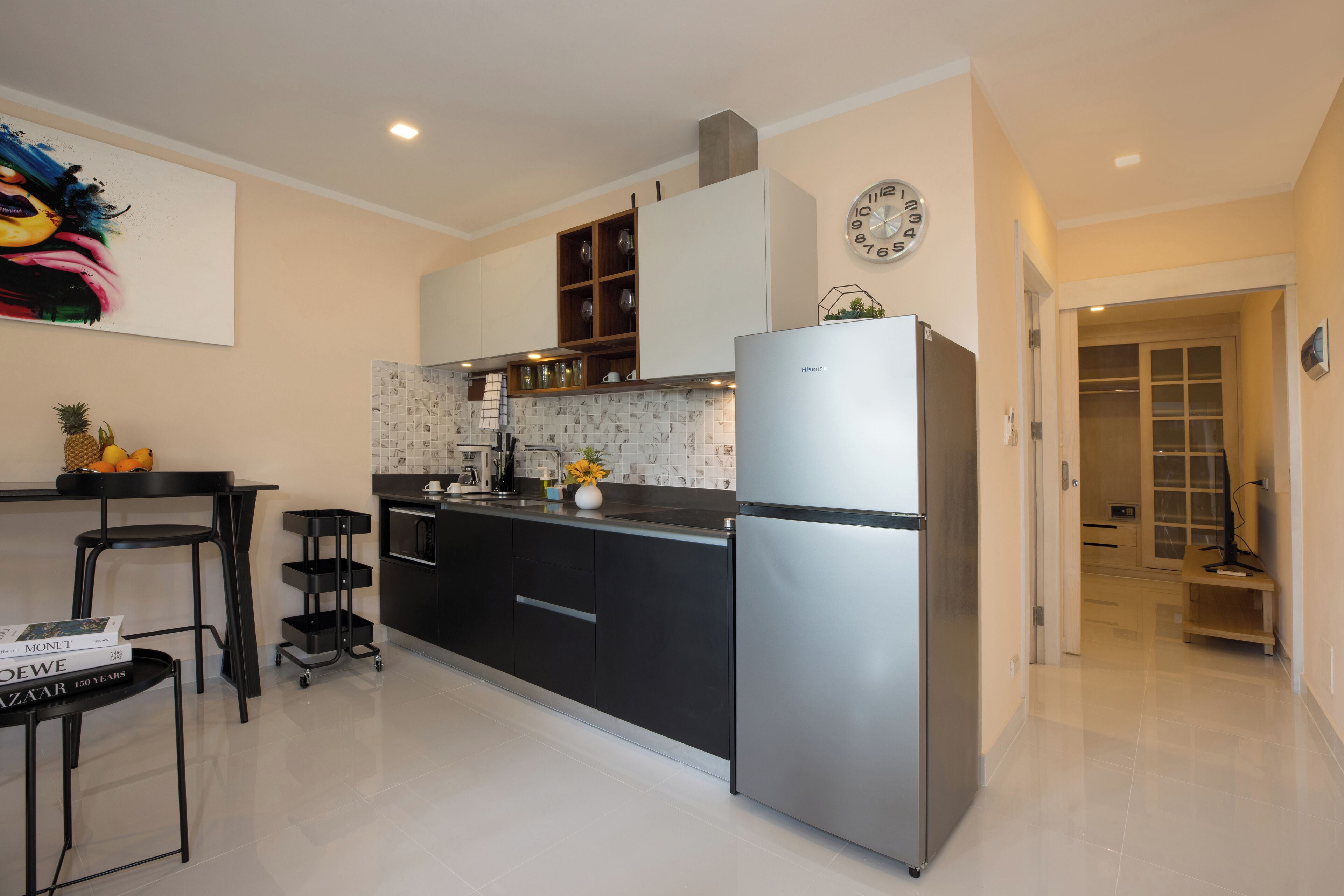A modern kitchen with black cabinets, a stainless steel refrigerator, and a tiled backsplash.
