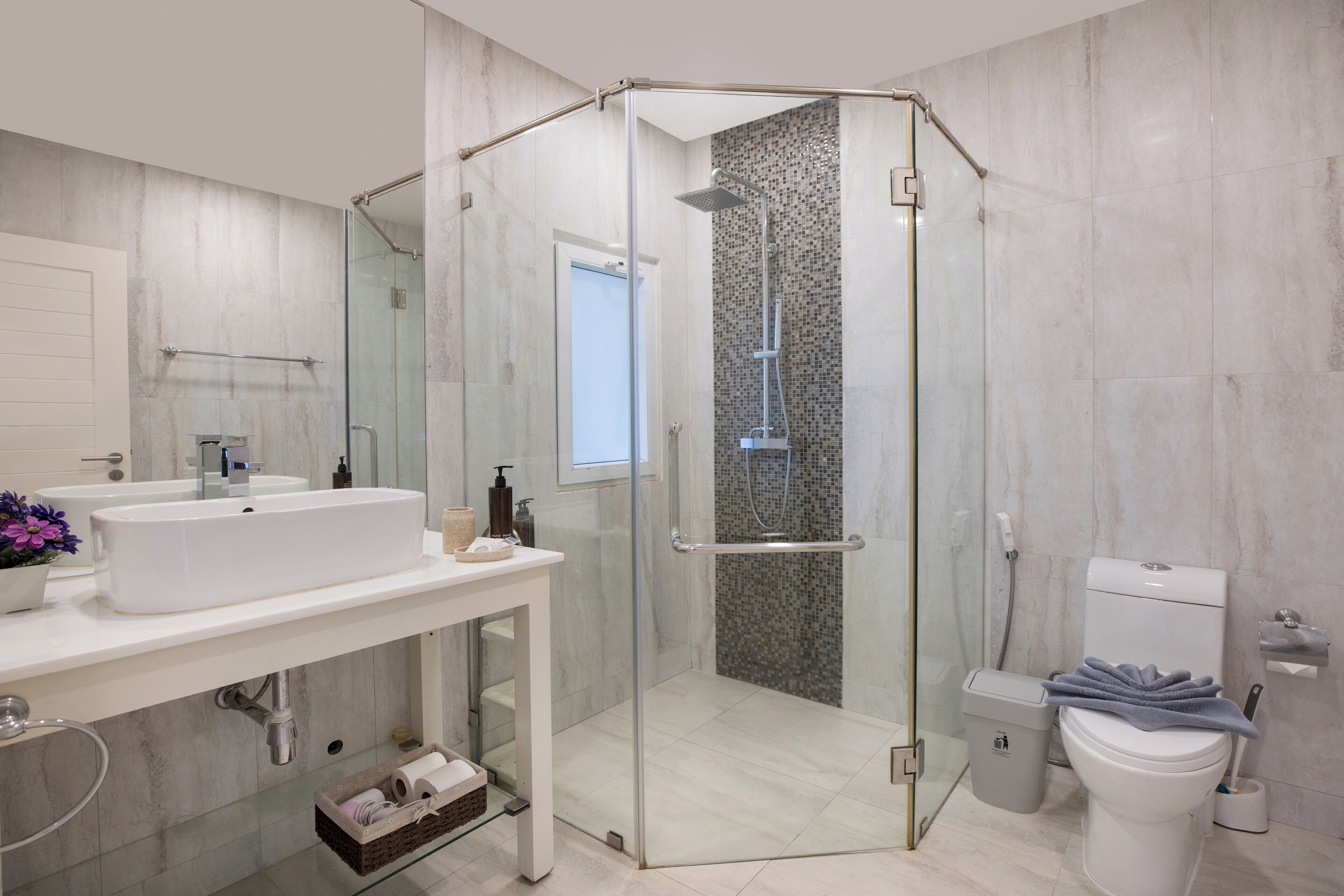 A modern bathroom with a glass-enclosed shower, a white sink, and a toilet.