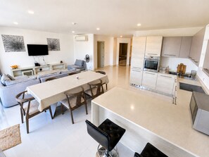 A modern kitchen with a dining area, built-in appliances, and a flat-screen TV.