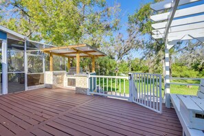 A wooden deck with a pergola, stone wall, and white railing. - Outdoor Kitchen & Gaming Garage: Bradenton Retreat (Bradenton)
