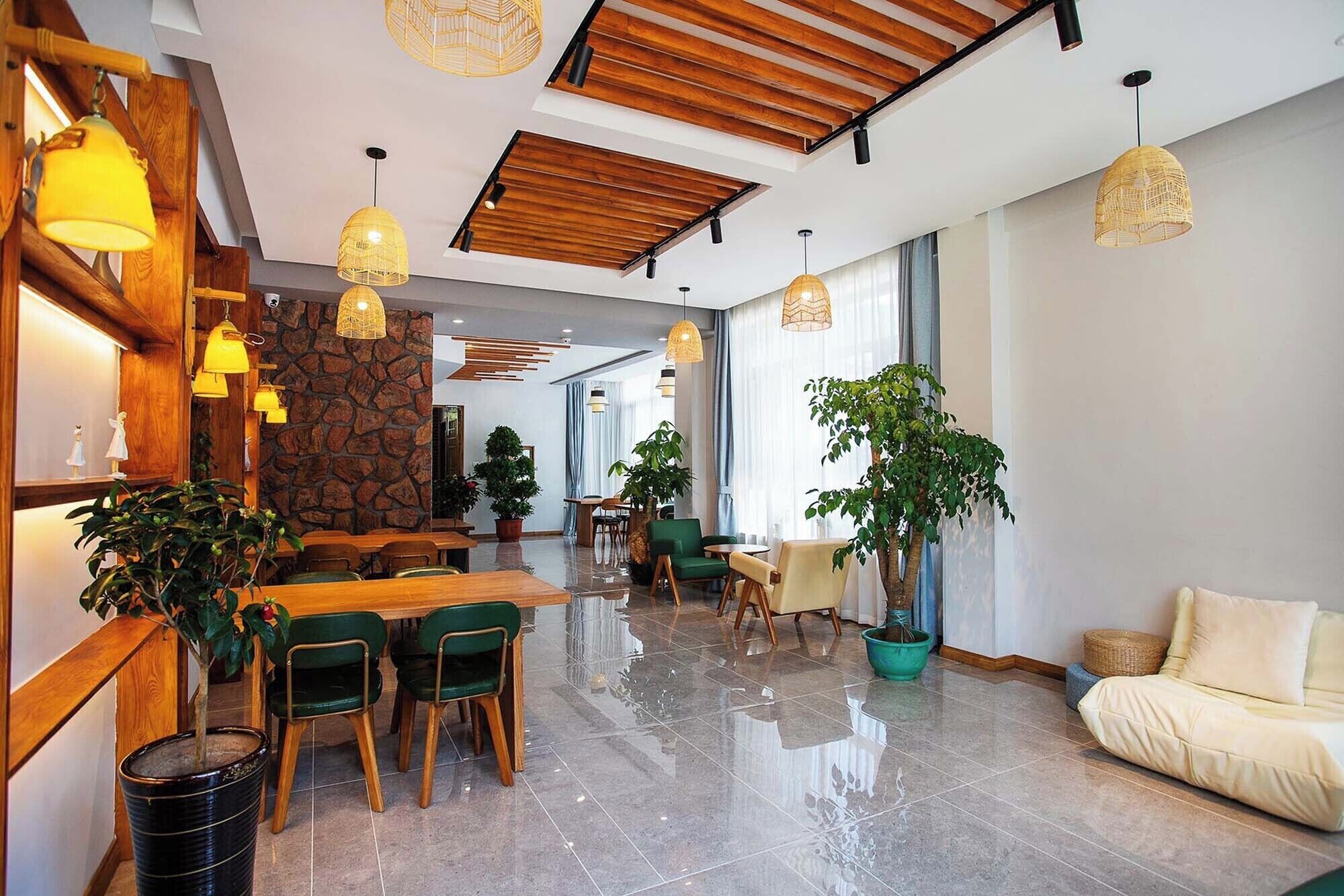 A spacious dining area with wooden tables and chairs, a stone accent wall, and hanging pendant lights.