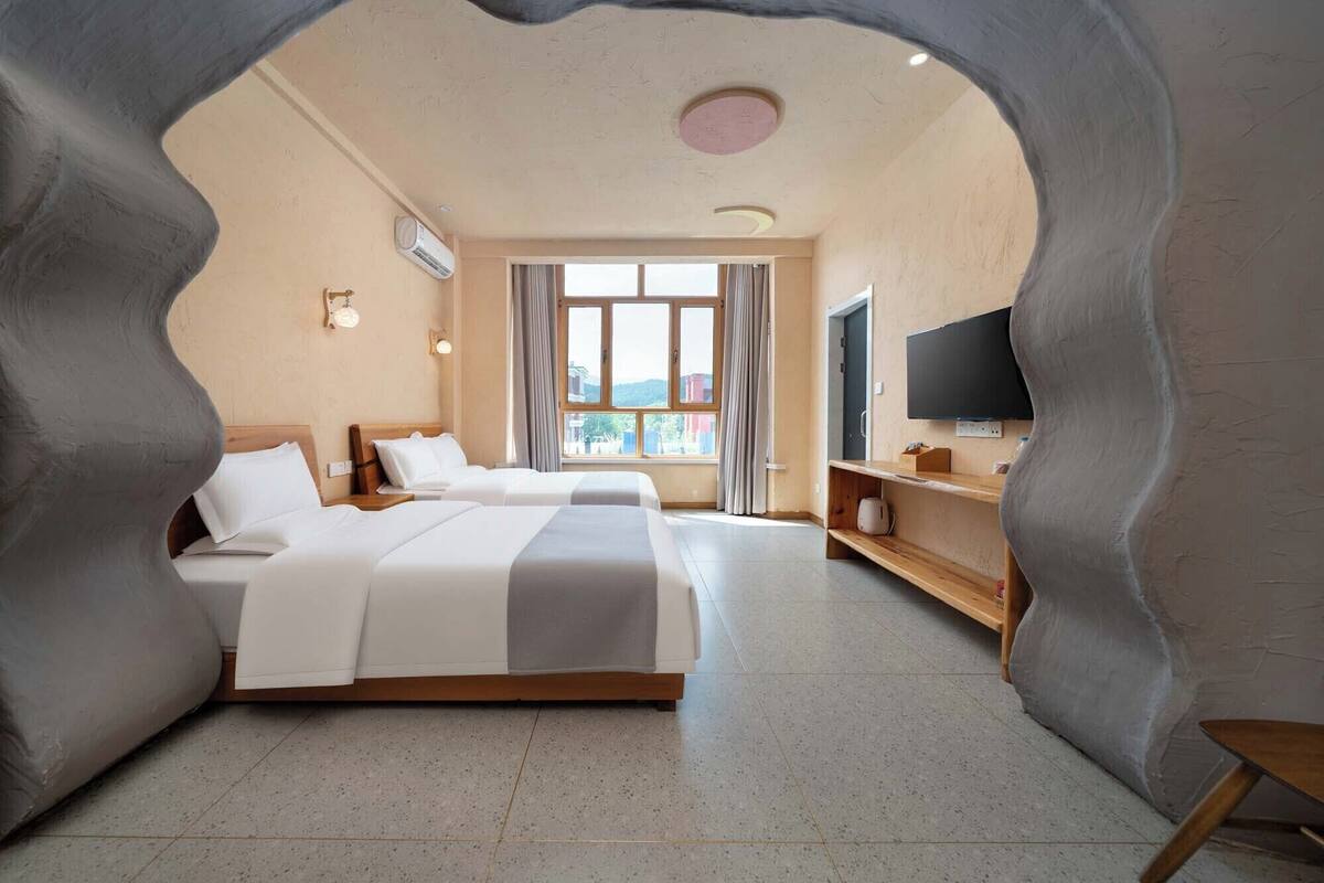 A hotel room with two beds, a TV, and a window with curtains.