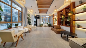A spacious, well-lit room with large windows, a wooden ceiling, and a variety of seating options including a sofa, chairs, and a bench. - Yabuli Liangqi Qingyun Homestay (Harbin)