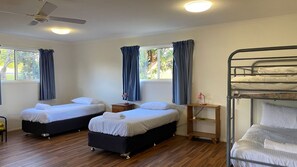 A hotel room with two beds, a bunk bed, wooden flooring, a ceiling fan, and a window with curtains. - Andagen has water glimpses (Bendalong)