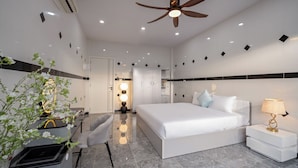 A modern hotel room with a large bed, a desk, a chair, a ceiling fan, and a bedside lamp. - Mei's house homestay (Da Nang)