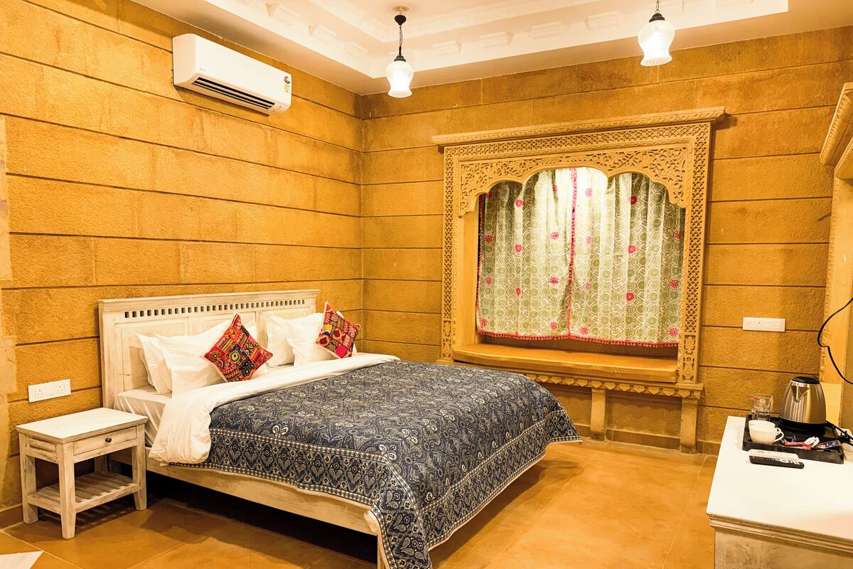 Une chambre à coucher avec un lit, une table de chevet et une fenêtre agrémentée de rideaux décoratifs.