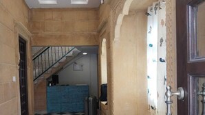 A hotel corridor with a checkered floor, a staircase, a reception desk, and a decorative door. - Mayra Boutique Casa (Jaisalmer)