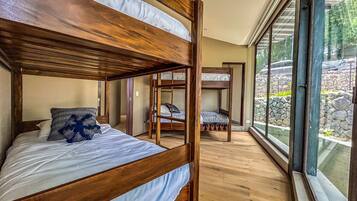 Ein Zimmer mit einem Etagenbett, einer kleinen Sitzecke und einem großen Fenster mit Blick ins Freie.