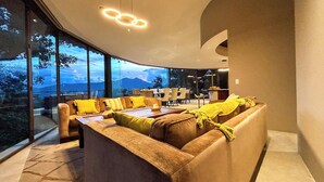 A modern living room with a curved ceiling, large windows, and a view of mountains.