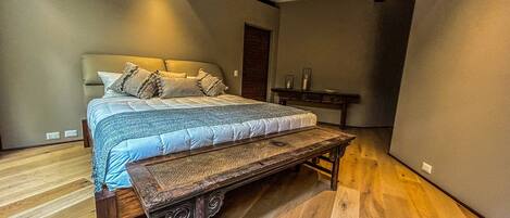 A bedroom with a large bed, a wooden bench, and a small table.