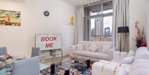 En moderne stue med en sofa, et sofabord og et fjernsyn, der viser "BOOK ME".