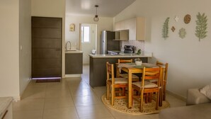 A modern kitchen with a central island, wooden dining table, and chairs.