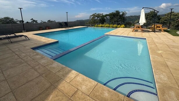 A rectangular swimming pool with a blue edge, surrounded by a tiled deck.