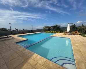 A rectangular swimming pool with a blue edge, surrounded by a tiled deck.