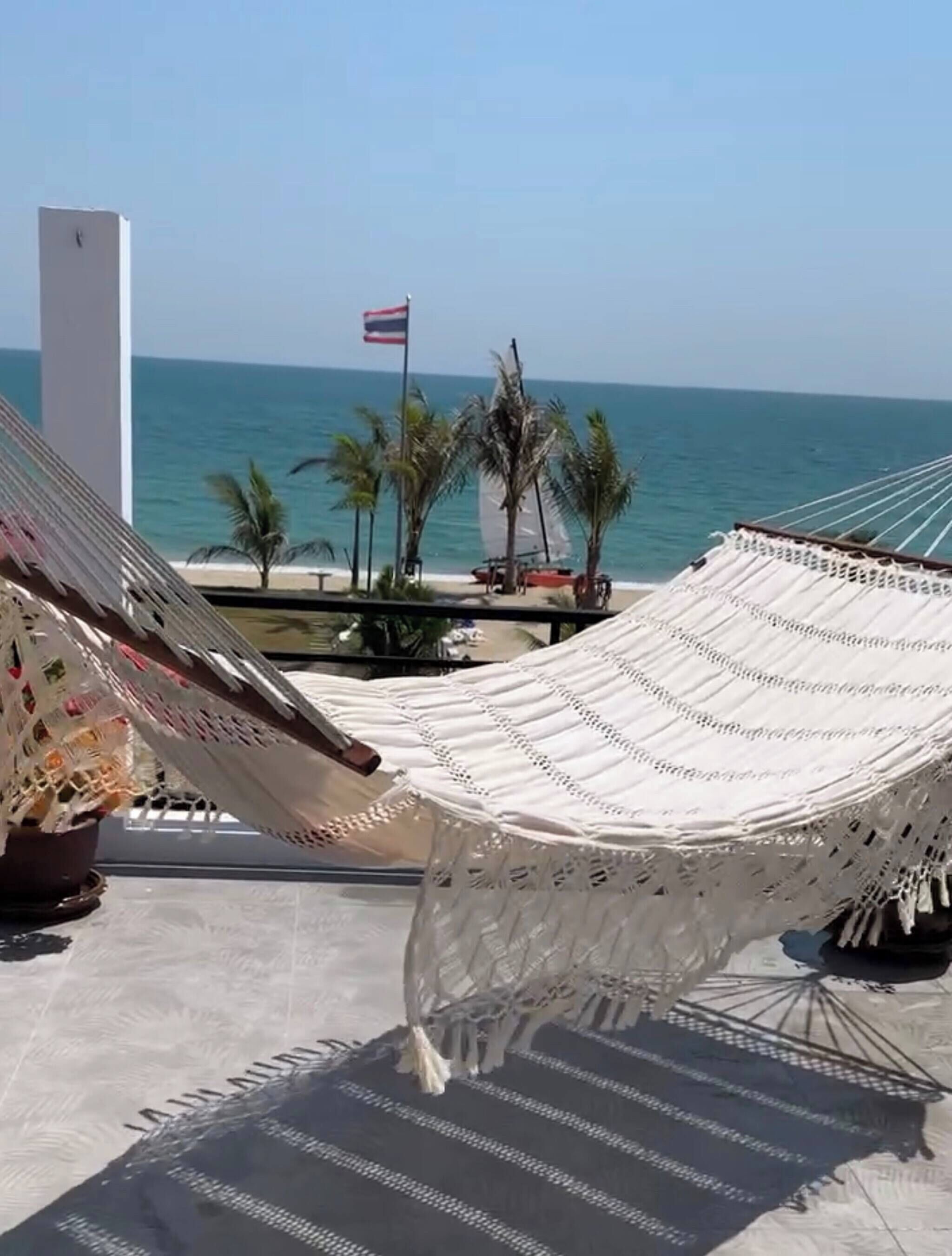 A hammock with a view of the sea and a flag.
