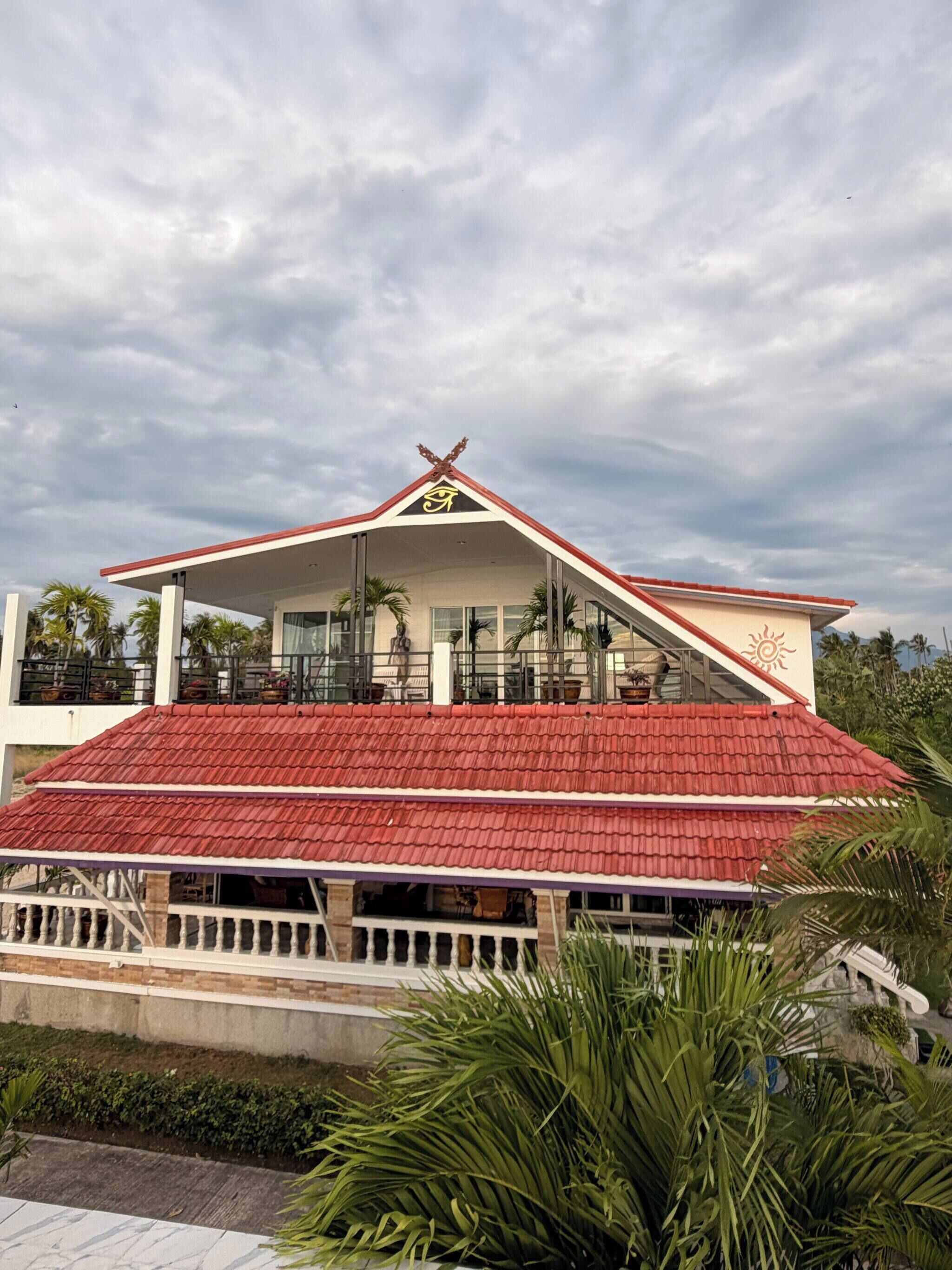 A building with a red roof and a white facade, featuring a prominent symbol on the roof.